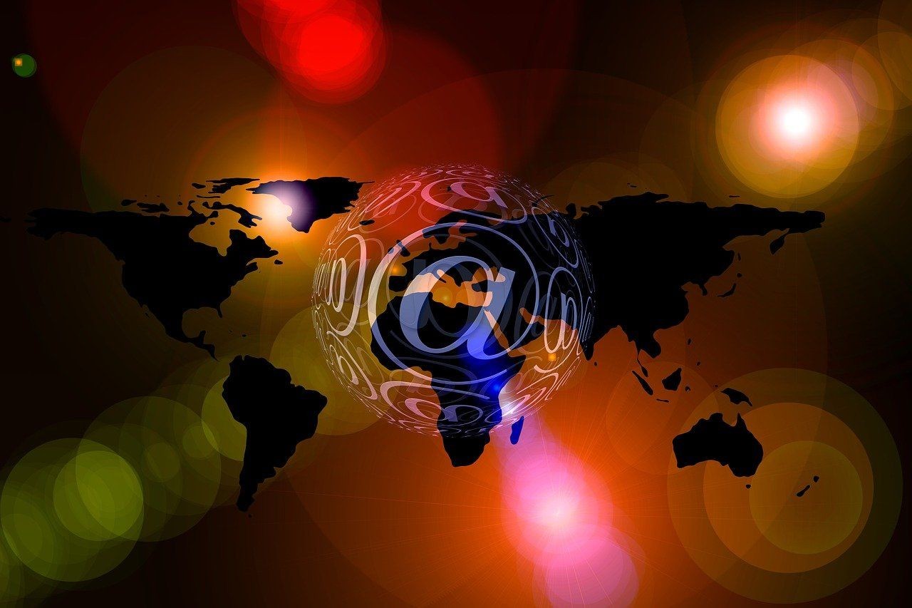 World map silhouette with glowing at symbol and colorful light effects.